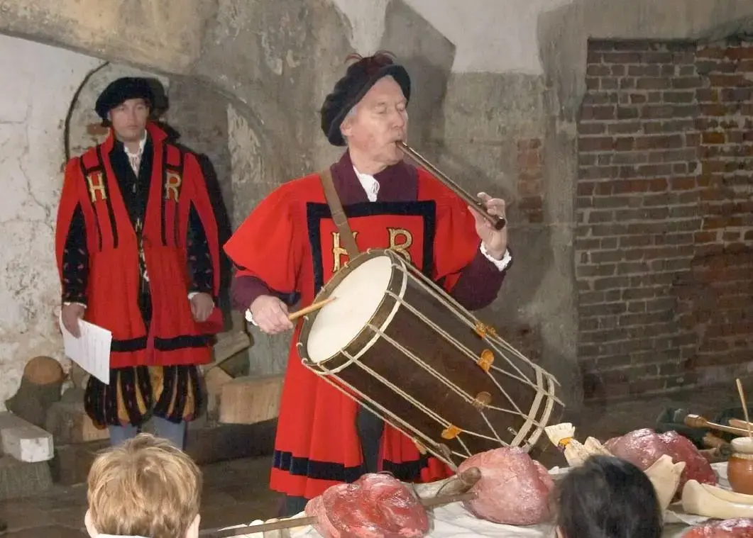 man in red traditional costume playing one handed snare drum